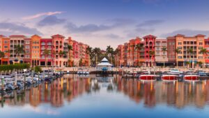 Naples bayfront buildings and marina reflected in the water at sunrise