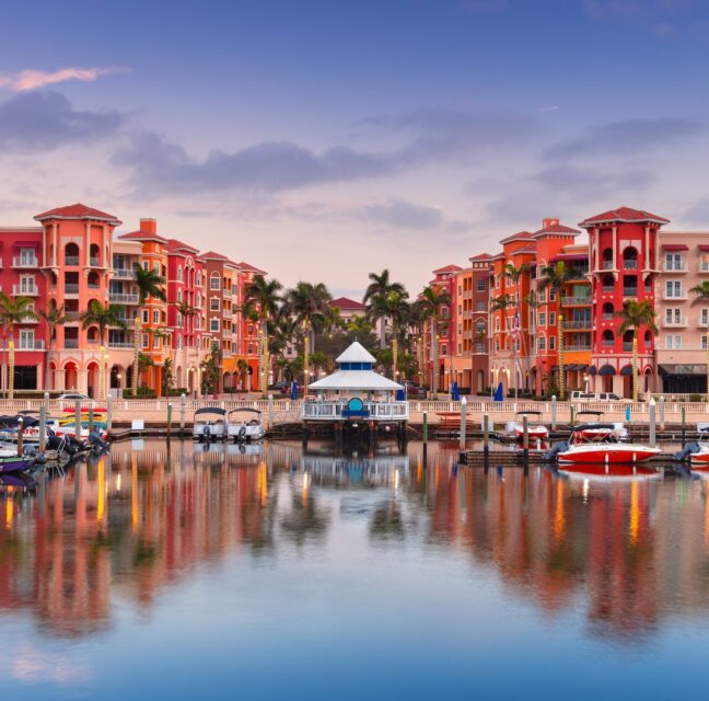 Naples bayfront buildings and marina reflected in the water at sunrise