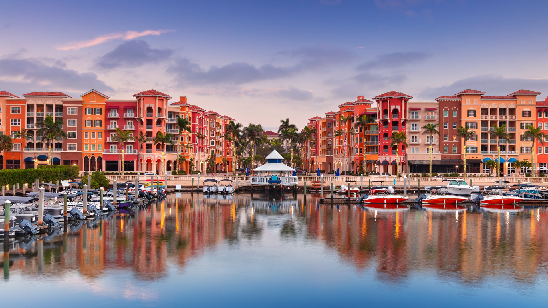 Naples bayfront buildings and marina reflected in the water at sunrise