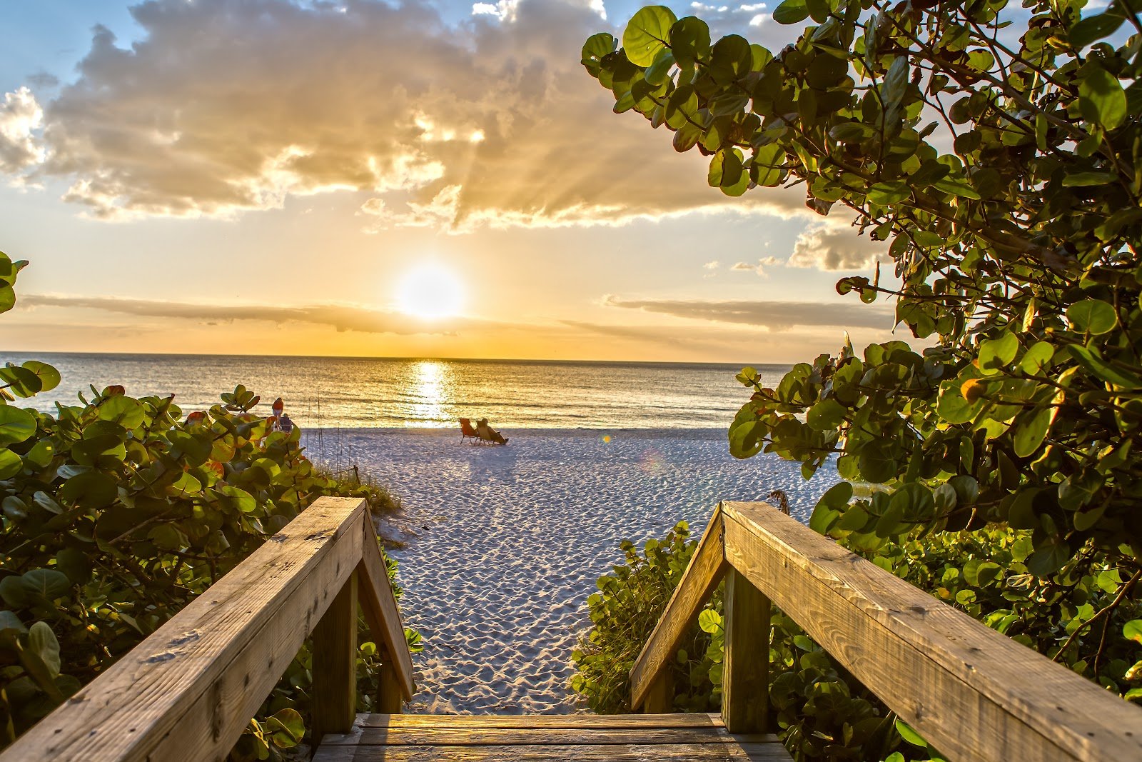 Boardwalk steps down to a Naples beach at sunset