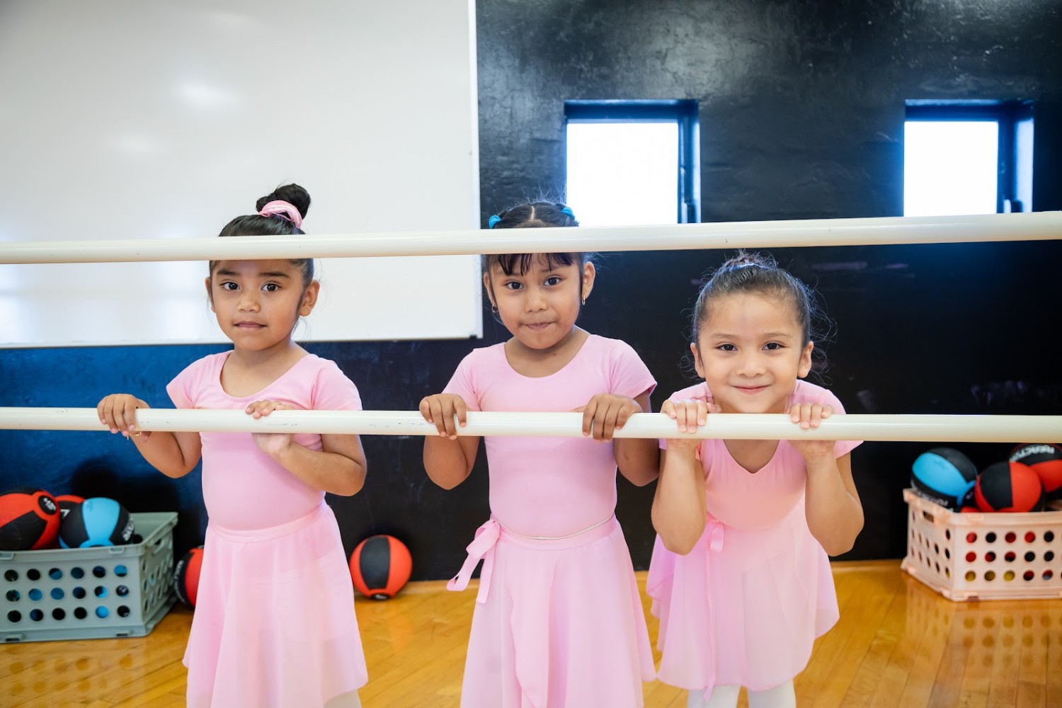 Three young dancers in ballet outfits at the barre during an RCMA dance class