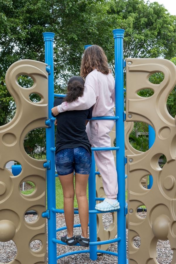 Two Youth Haven teens on a playground climbing structure, arms around each other