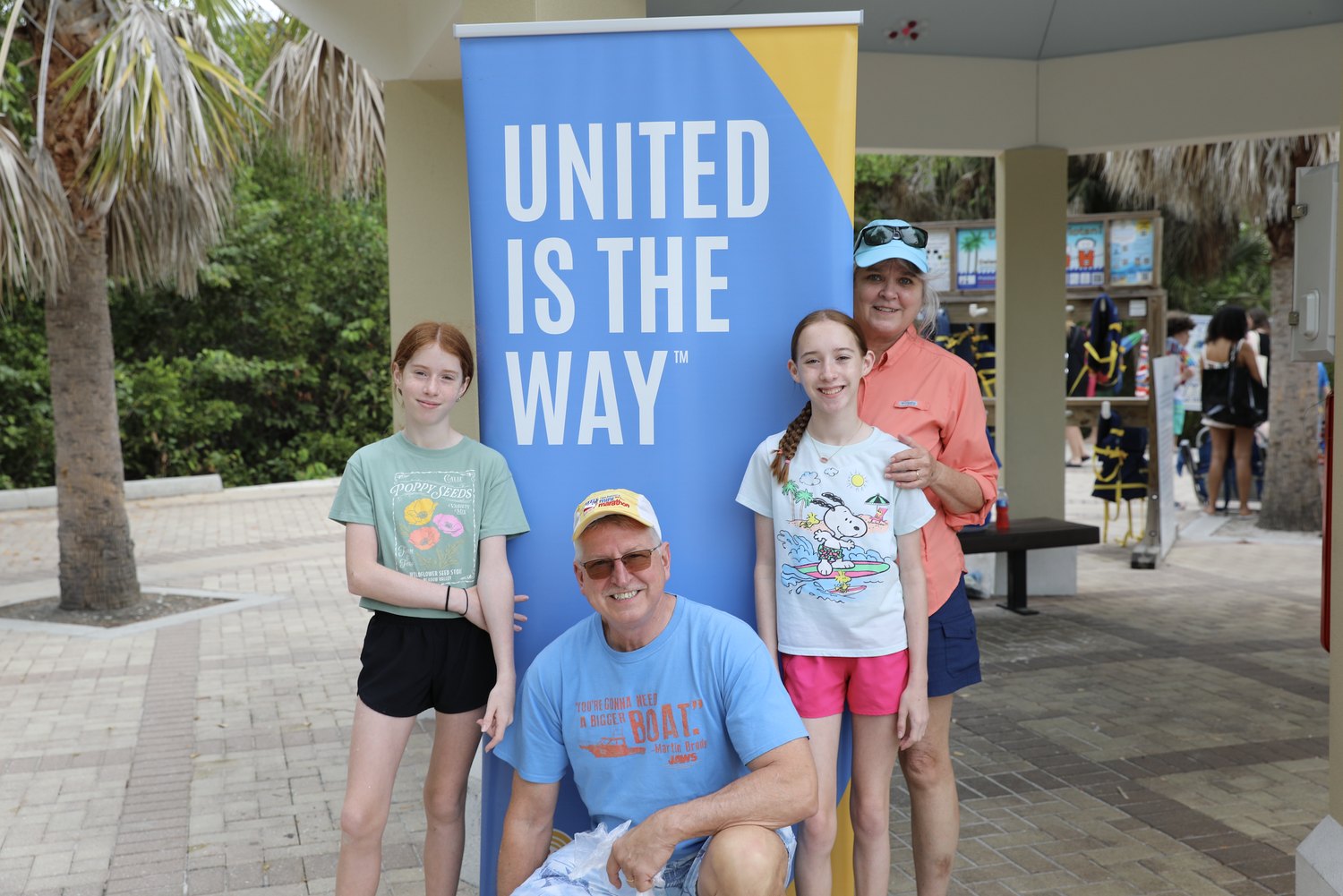 Volunteers and two girls beside a United Way banner at Clam Pass