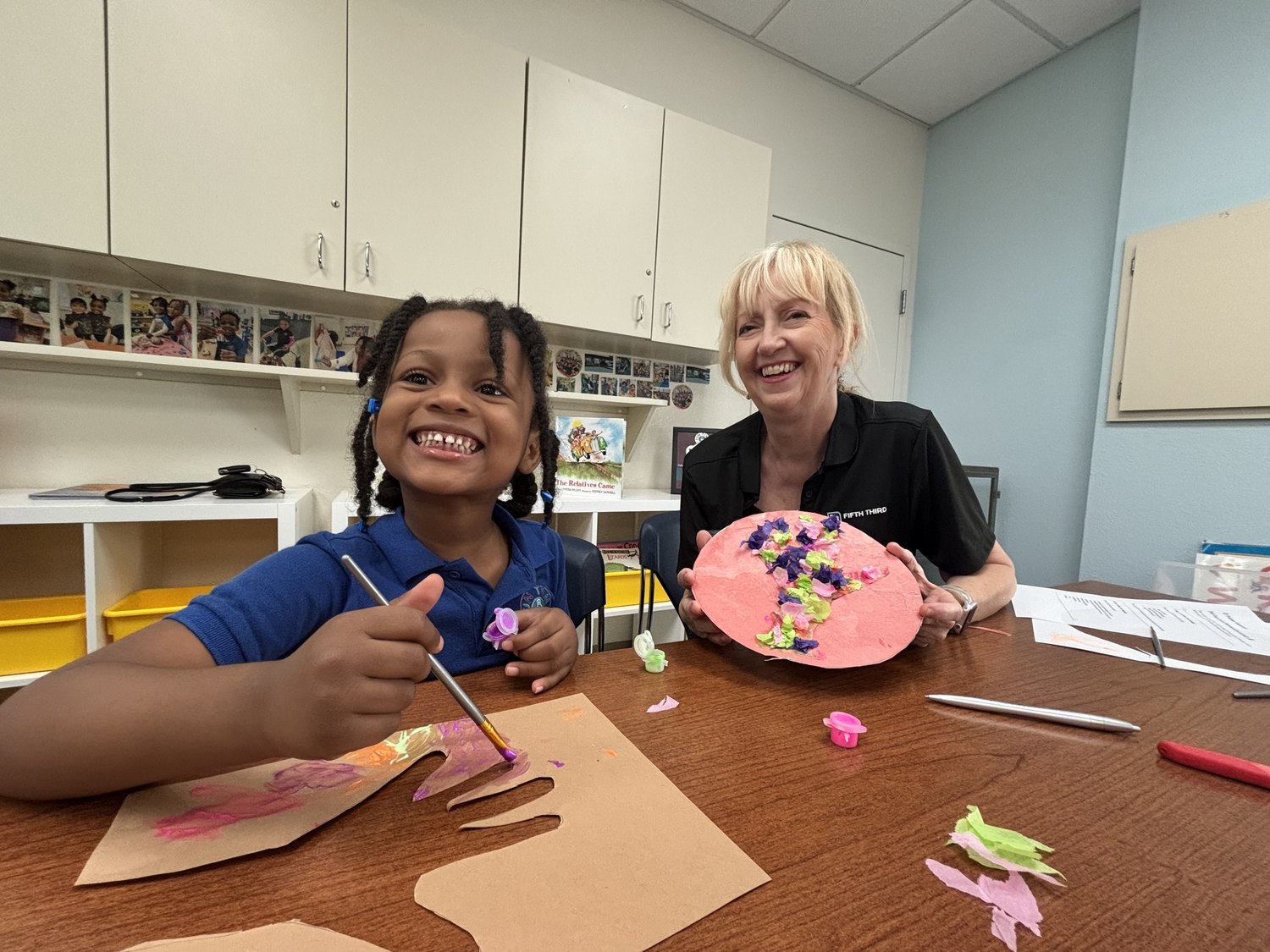Women United volunteer helping a child with a craft at Fun Time Academy