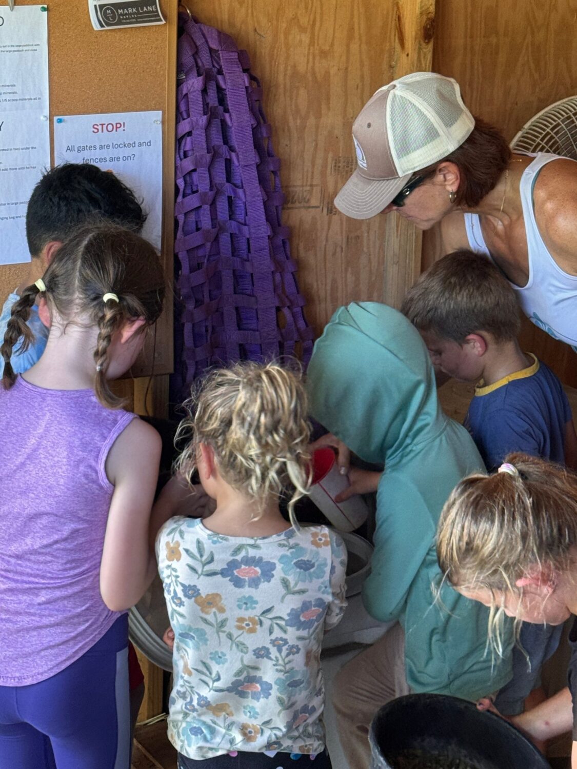 Children measuring vitamins into feed buckets during Tuesday Night Tuck-In