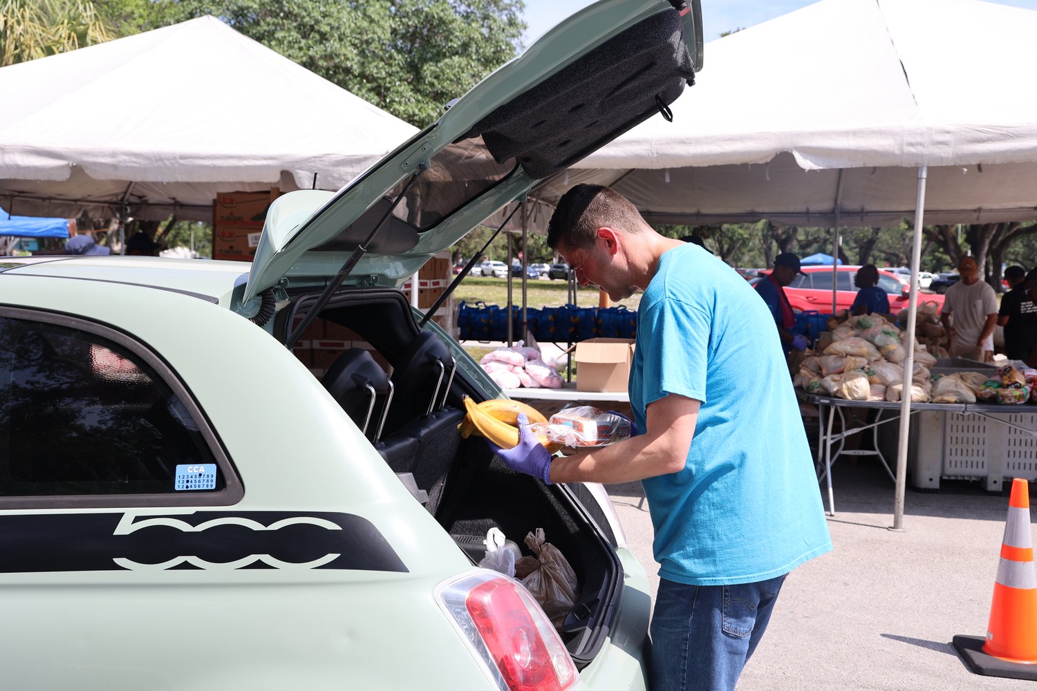 Volunteer loading groceries into a car trunk at a Farm Share distribution