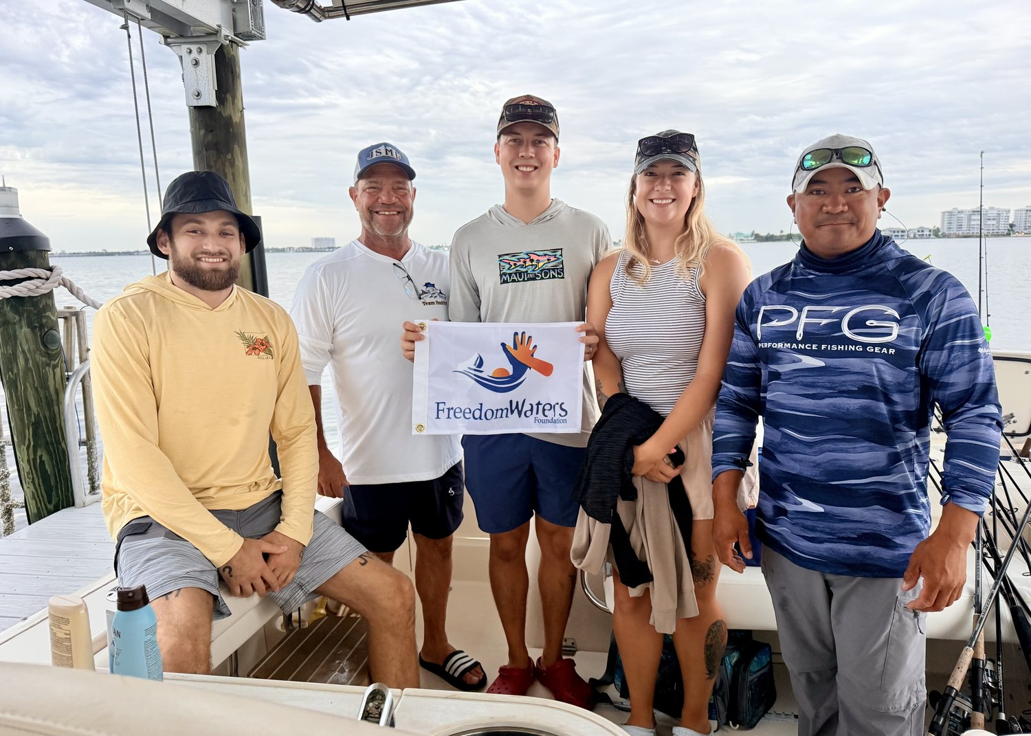 Five people on a boat holding a Freedom Waters Foundation banner