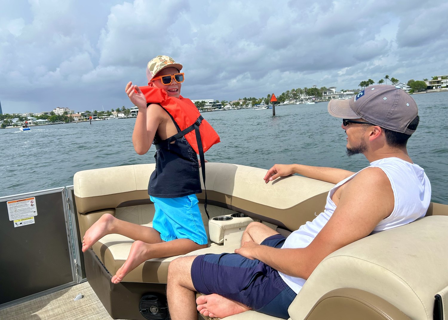 Smiling child in a life vest sitting on a pontoon boat with a volunteer