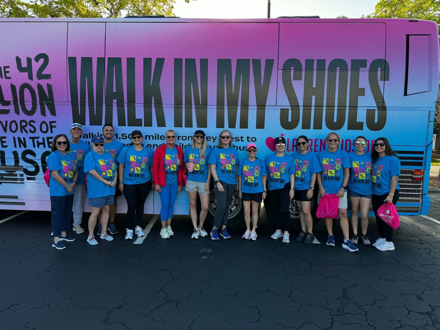 Team in matching shirts beside the Walk in My Shoes tour bus