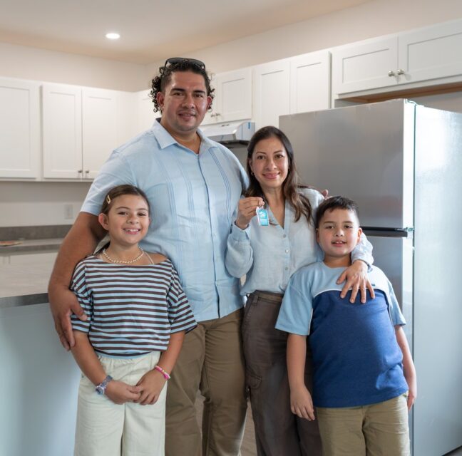 Family of four holding keys in the kitchen of their new Habitat home