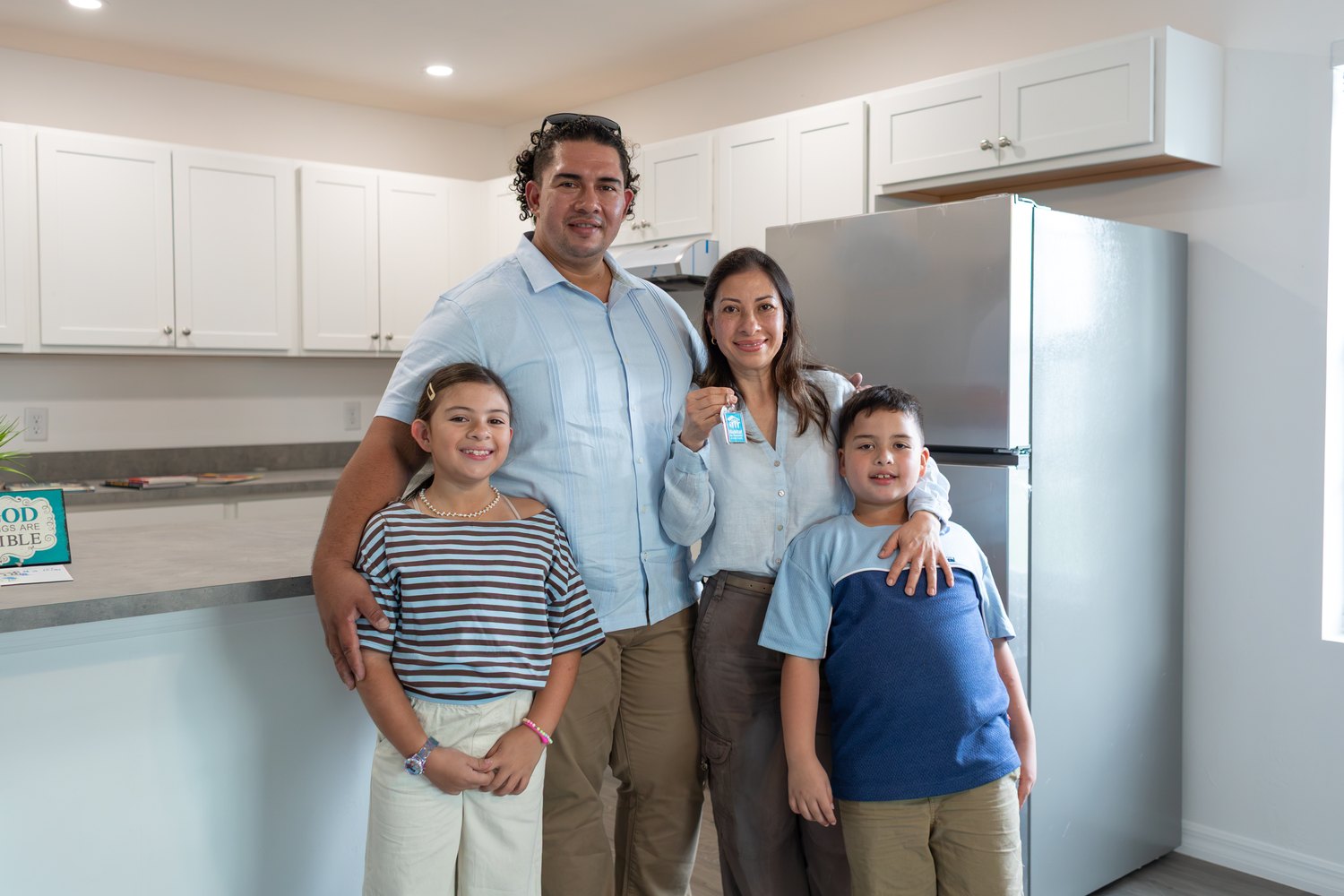 Family of four holding keys in the kitchen of their new Habitat home