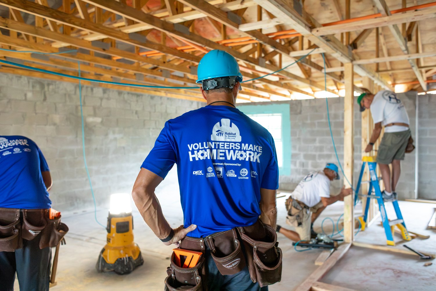 Volunteers in Habitat shirts framing the interior of a home under construction