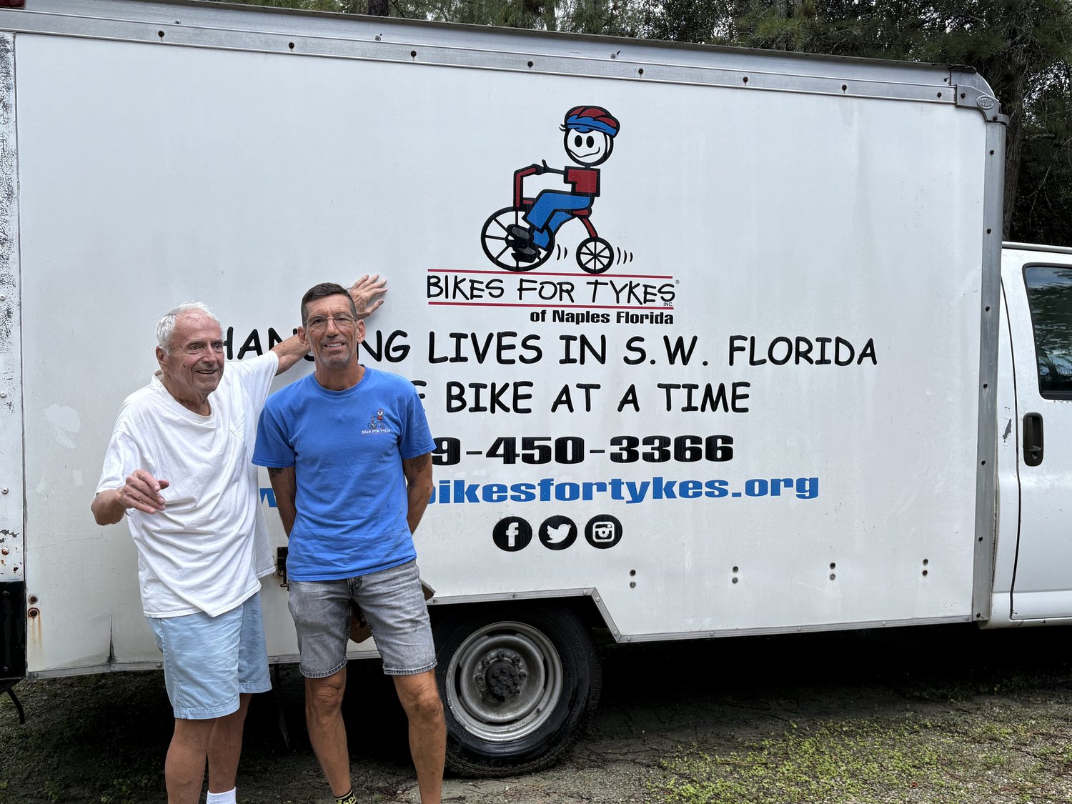 Two men beside the Bikes for Tykes truck after a bicycle donation