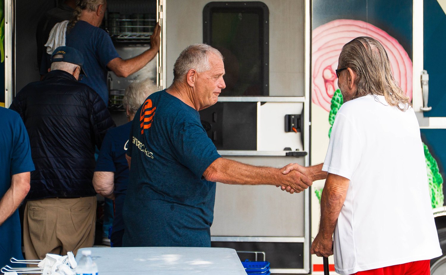 Volunteer shaking hands with a veteran at the mobile market