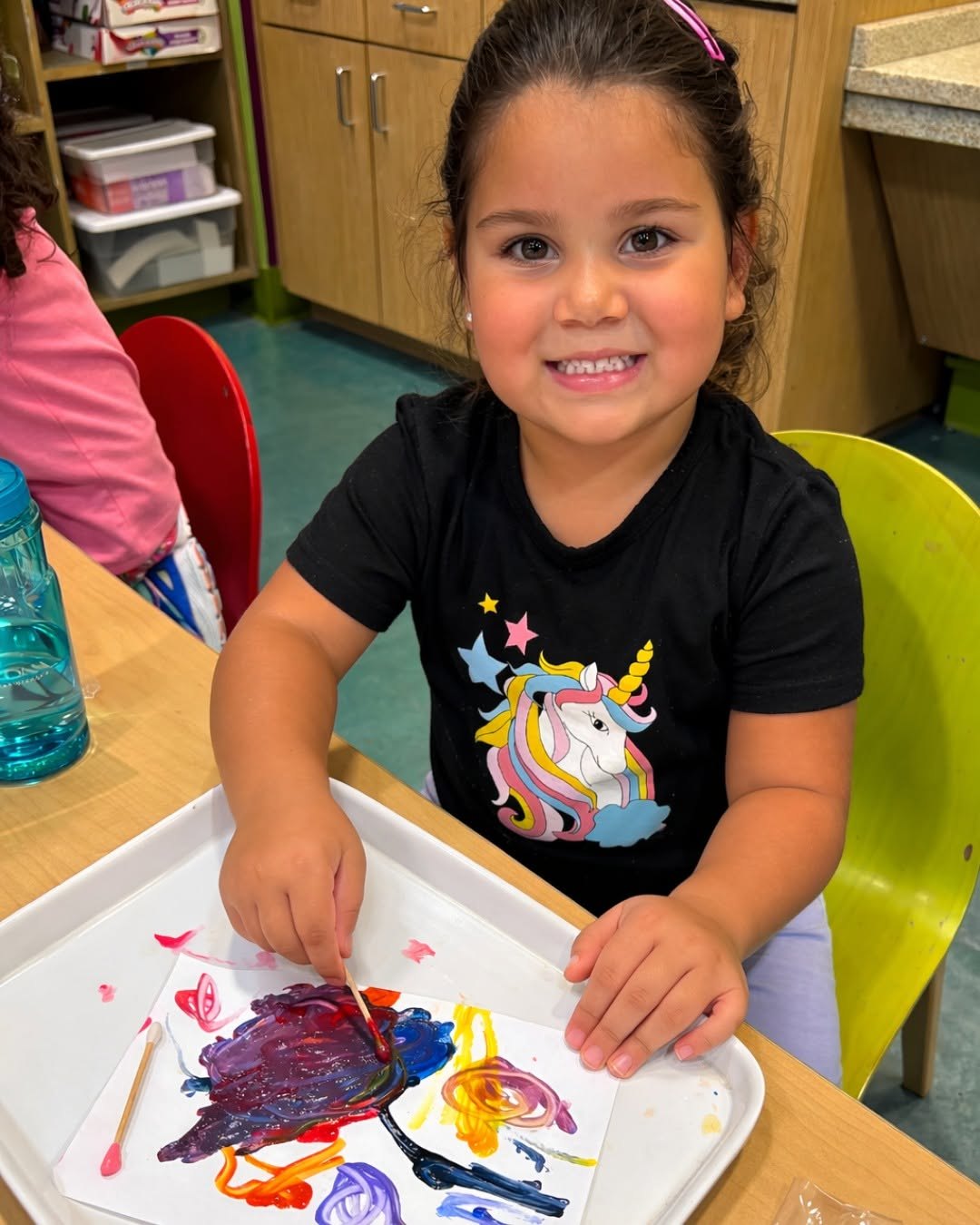 Young girl smiling while finger painting at a museum craft table