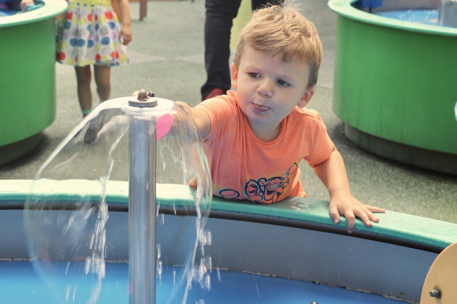Toddler playing at an interactive water table exhibit
